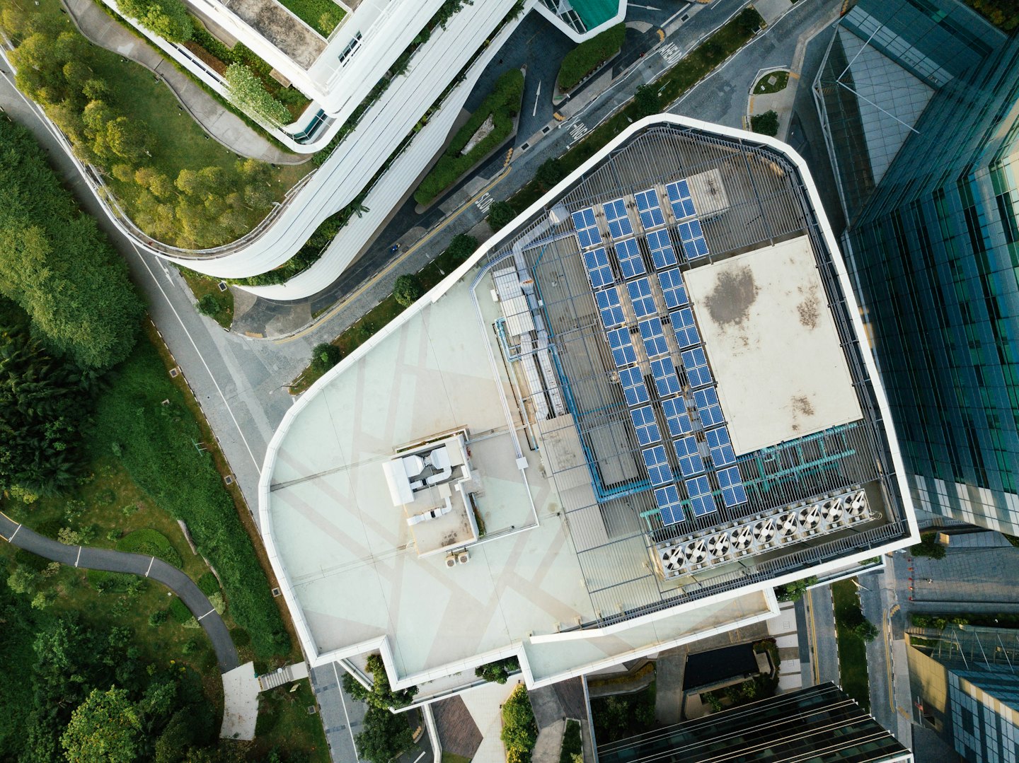 Paneles solares en el techo de un edificio verde con caminos sinuosos.