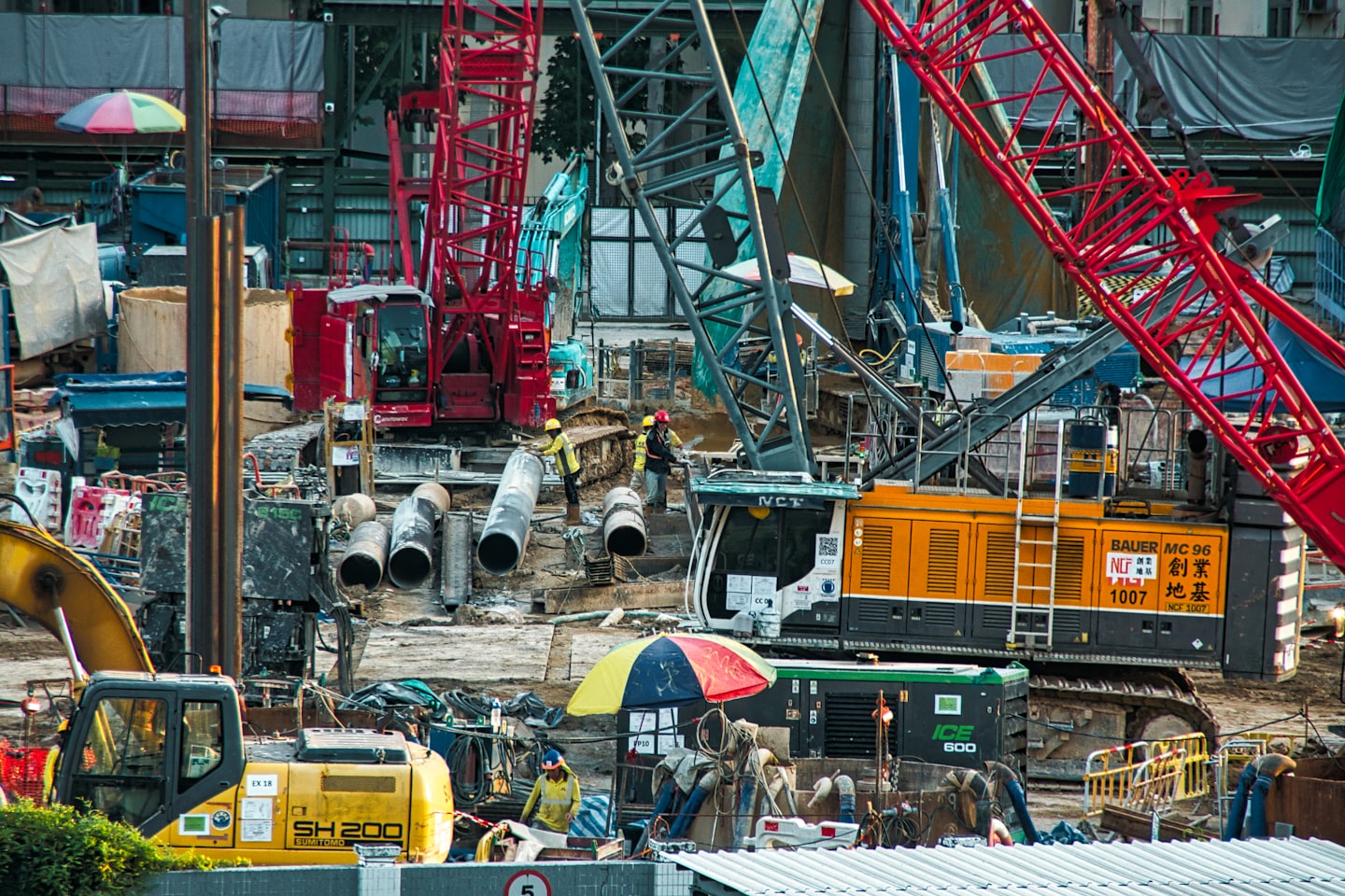 Trabajadores de la construcción y maquinaria pesada en un gran sitio al aire libre.