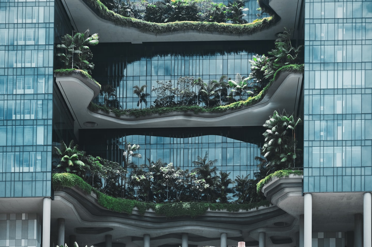 Edificio moderno con balcones escalonados llenos de plantas tropicales.